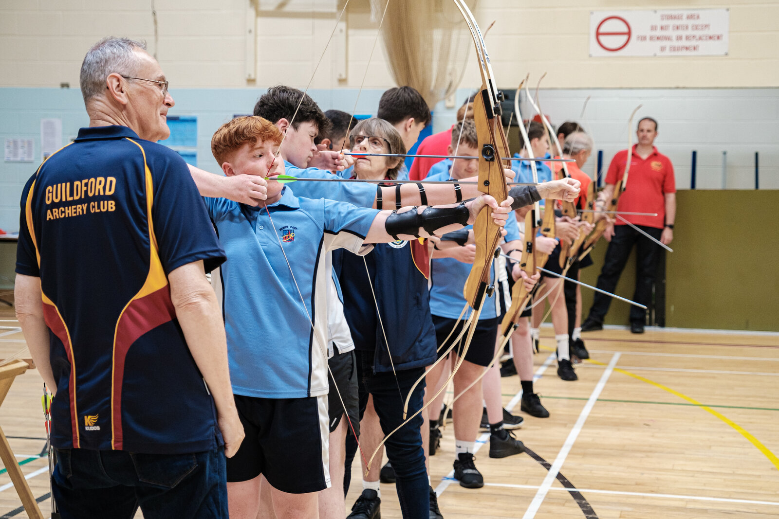 Students doing archery watched by a coach