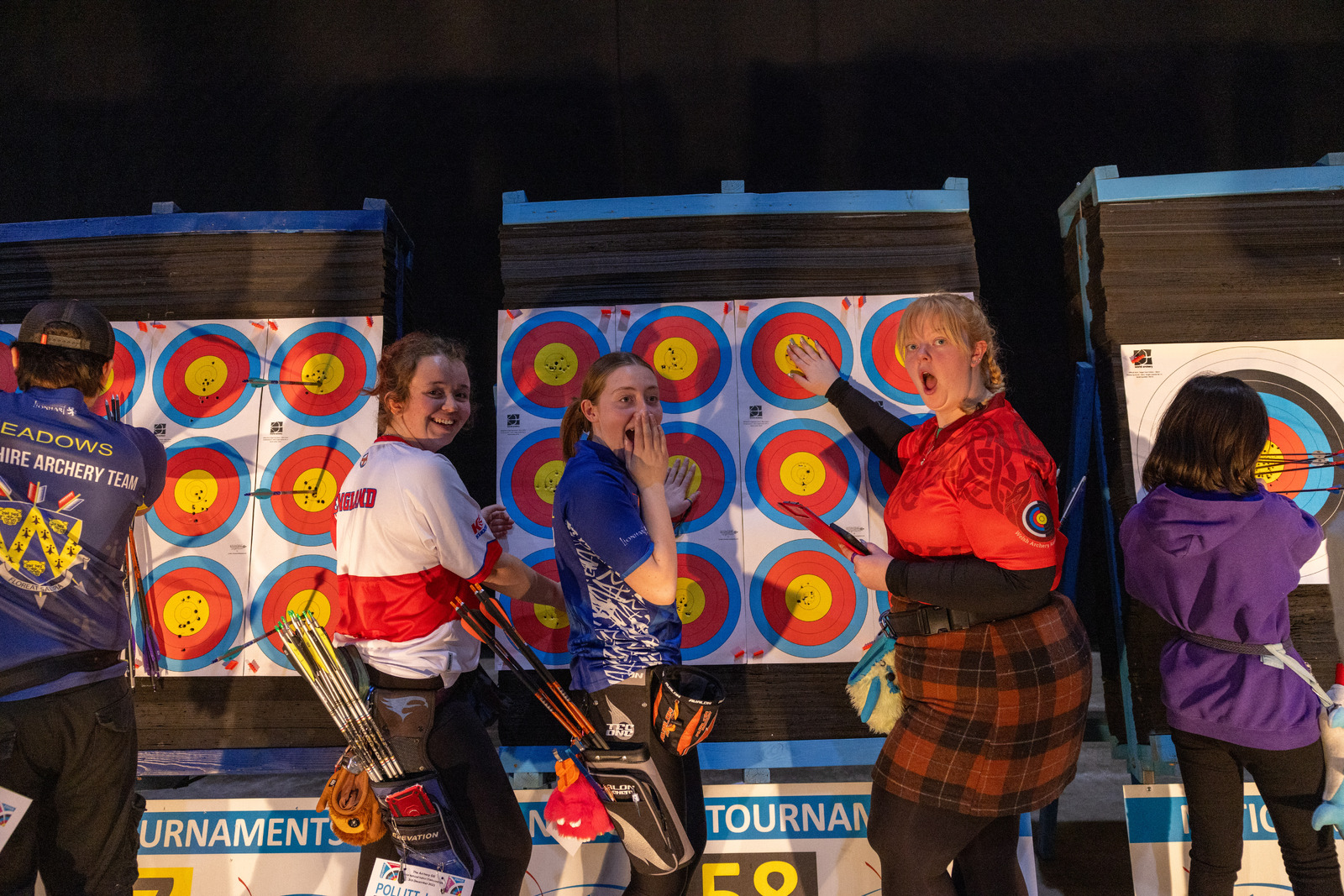 Young archers pointing at arrows in a target and smiling